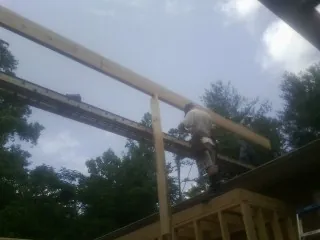 Carpenter setting a ridge beam over a new addition frame — Ice Dam Removal by Roofing Brothers in Davidson