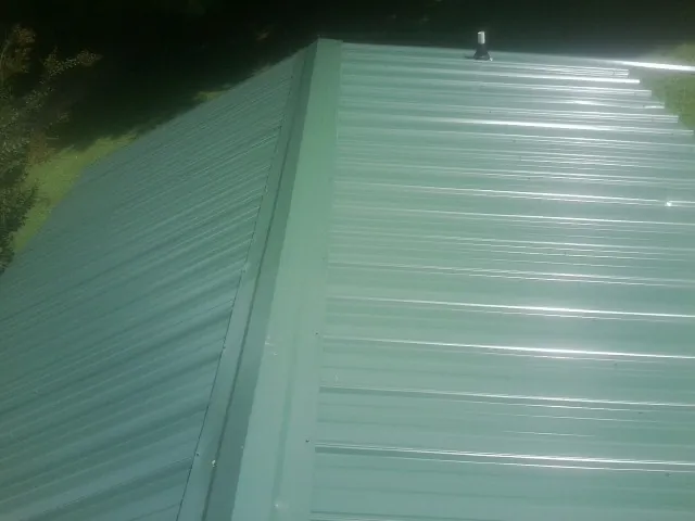 New green metal panels meeting at the ridge of a roof — Flat Roof Repair work by our crew in Davidson