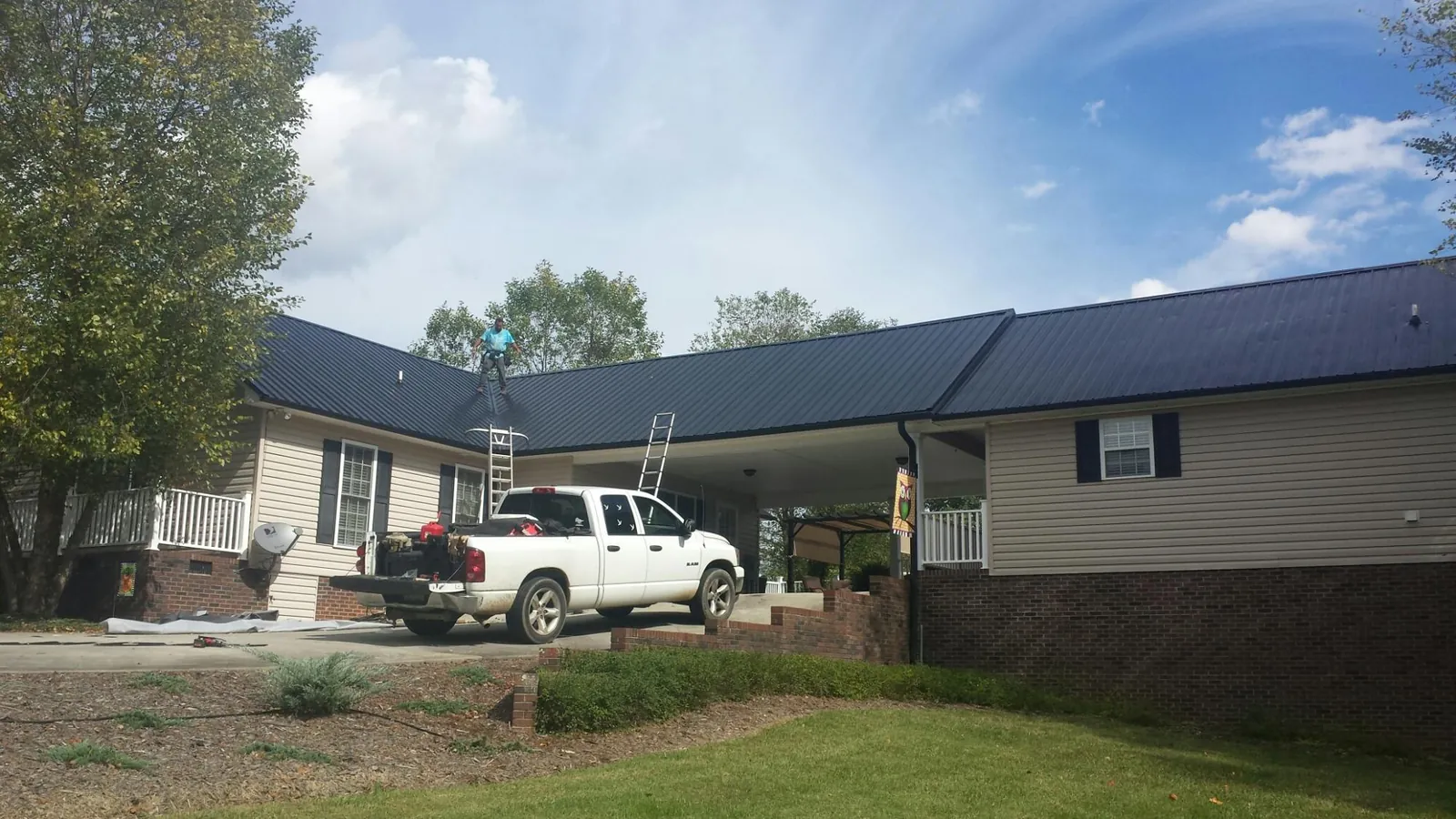 Black metal roof over a home and attached breezeway with ladders set in Davidson