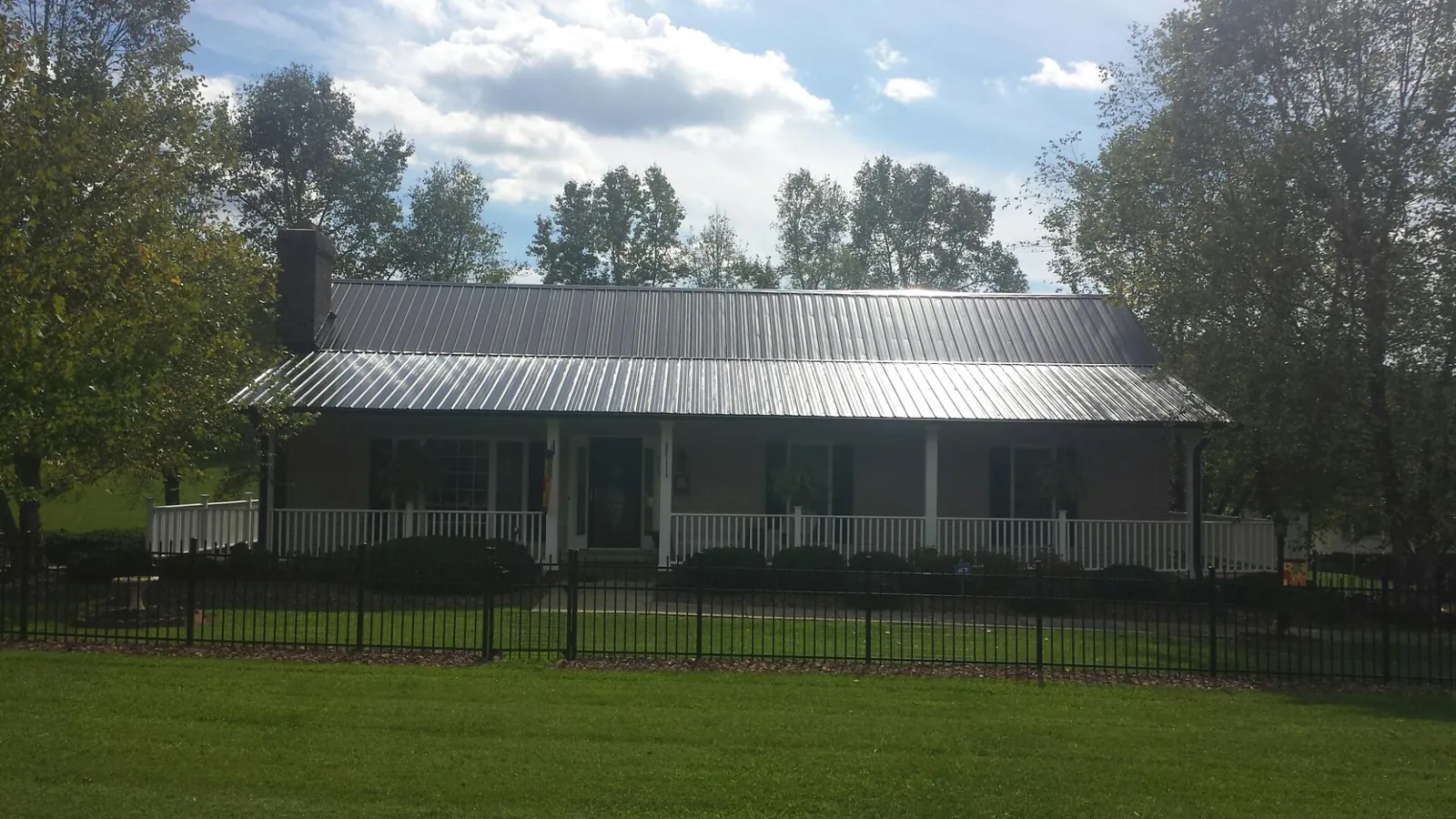 Gray metal roof on a brick ranch with a full width front porch — Gutter Guard Installation work by our crew in Davidson
