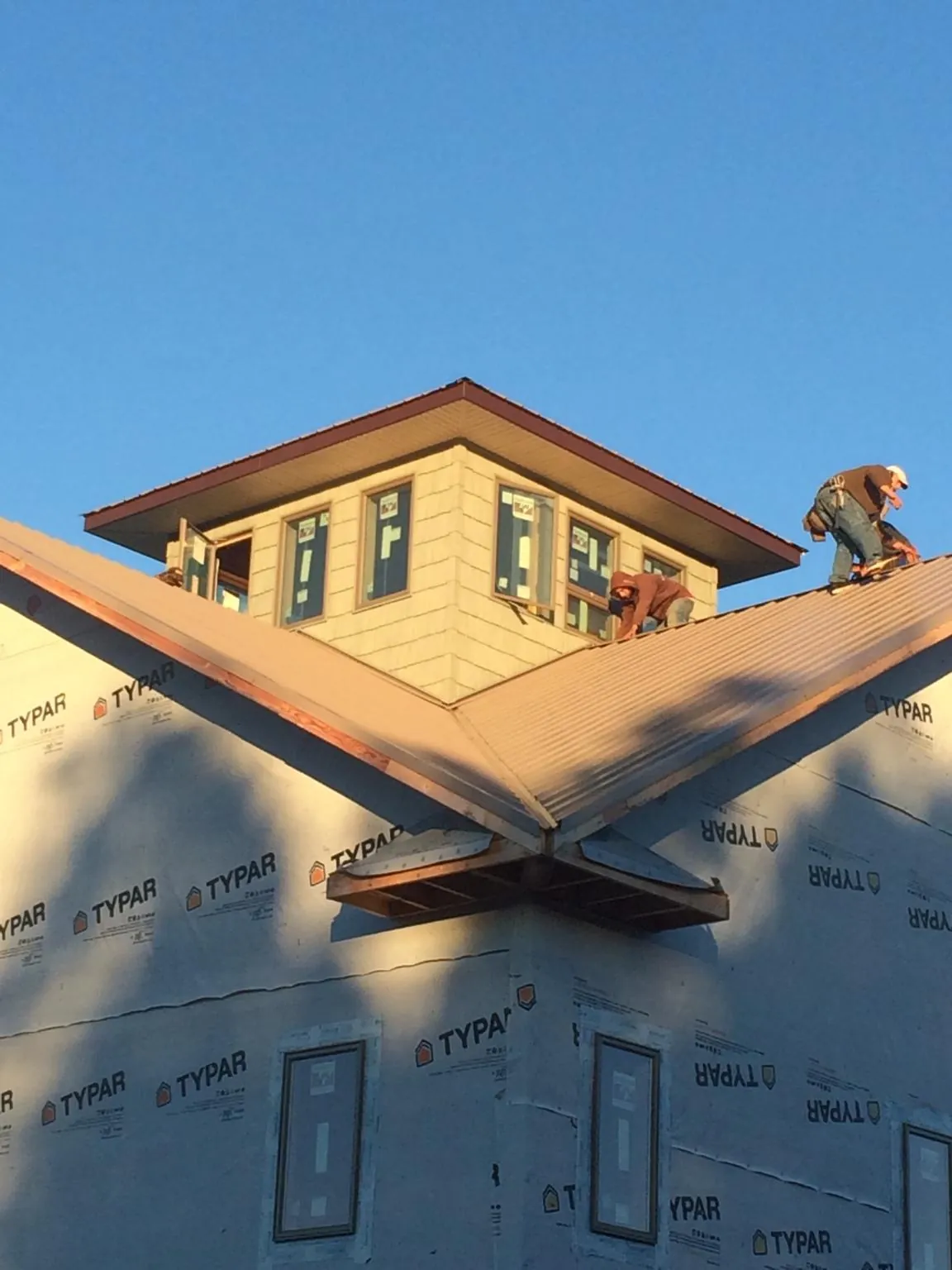 Roofers working around a rooftop cupola on a new metal roof at sunset — Roof Waterproofing in Davidson by Roofing Brothers